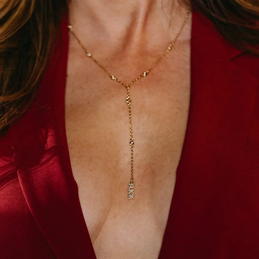 Gold necklace with a pendant worn by a person in a red garment.