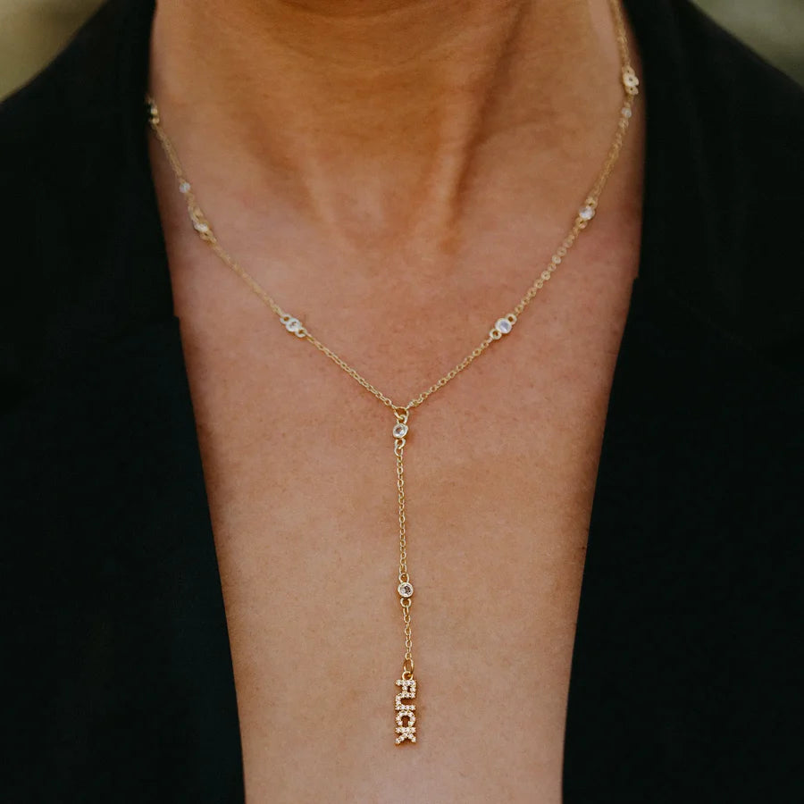 Gold necklace with  pendant on a person wearing a black top.